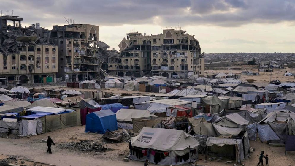 dpatopbilder - Ein Zeltlager für vertriebene Palästinenser steht neben zerstörten Häusern und Gebäuden. Foto: Jehad Alshrafi/AP/dpa