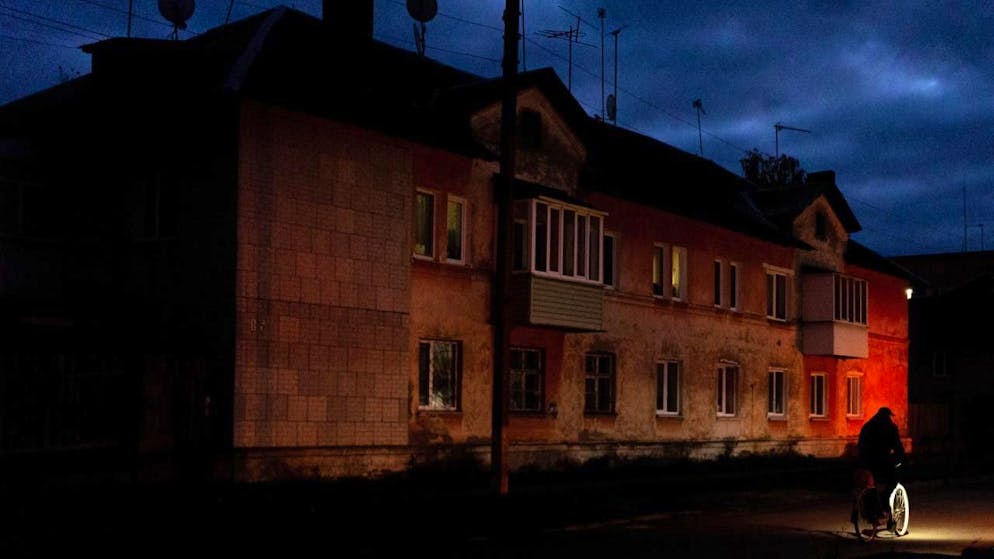 Eine Person fährt während eines Stromausfalls mit dem Fahrrad durch eine dunkle Wohnstraße. Foto: Julia Demaree Nikhinson/AP/dpa