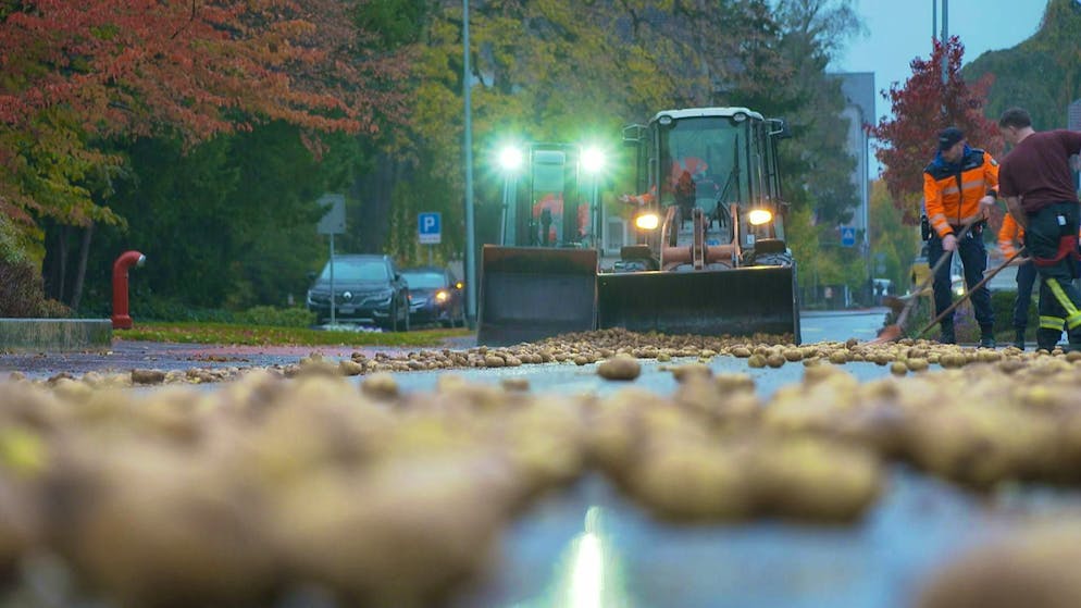 Workers are busy clearing the potatoes from the road. 