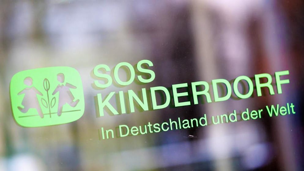 ARCHIV - Der Schriftzug «SOS Kinderdorf - In Deutschland und der Welt» ist an einer Glasscheibe an der Zentrale der Kinderhilfsorganisation SOS-Kinderdorf zu sehen. Eine Kommission legte einen Bericht zu Grenzüberschreitungen gegenüber Kindern vor. Foto: Matthias Balk/dpa/Archivbild