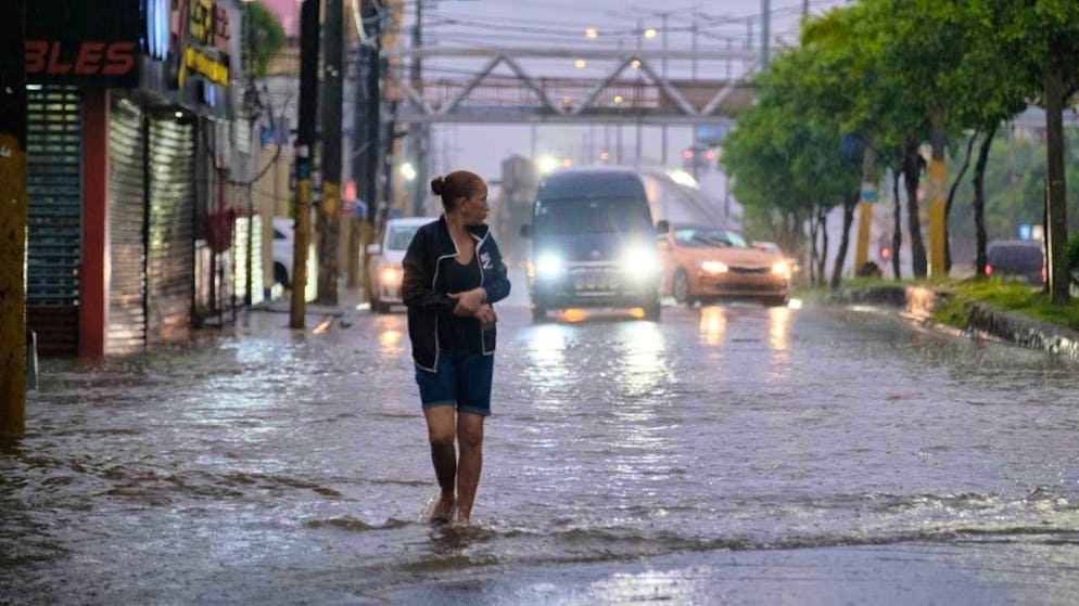 A woman walks through a street in Santo Domingo that was flooded by the rains of Tropical Storm Melissa. Photo: Ricardo Hernandez/AP/dpa