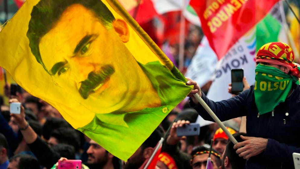 ARCHIV - Ein Jugendlicher hält eine Fahne mit dem Bild des inhaftierten Anführers der verbotenen kurdischen Arbeiterpartei PKK, Öcalan. Foto: Lefteris Pitarakis/AP/dpa/Archivbild