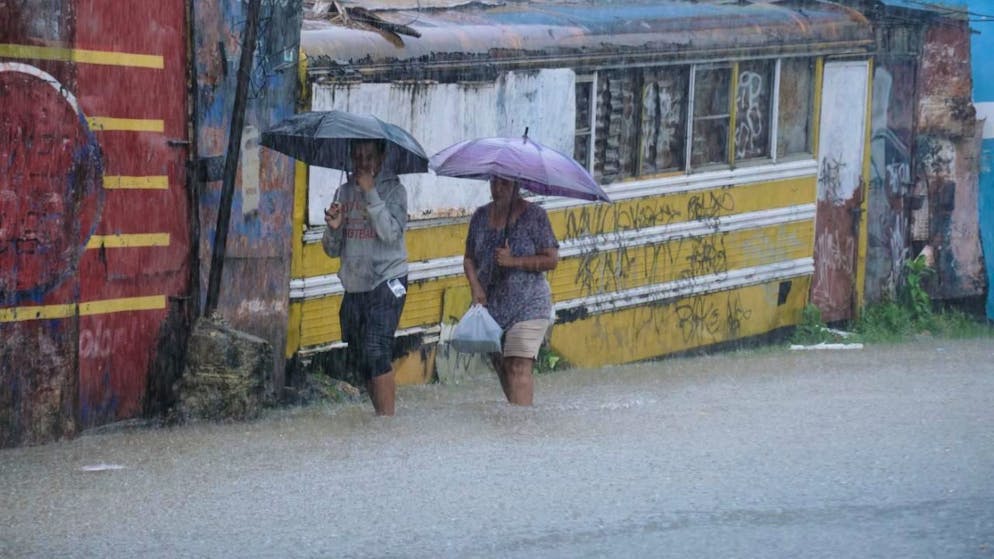 Des habitants traversent une rue inondée par les pluies provoquées par la tempête tropicale Melissa à Saint-Domingue en République dominicaine vendredi.,