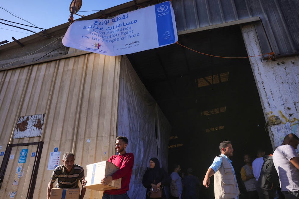 Des Palestiniens récupèrent des boîtes de rationnement alimentaire fournies par le Programme alimentaire mondial (PAM) dans un centre de distribution du village d'Al-Zawayda, à Gaza, le 27 octobre 2025.