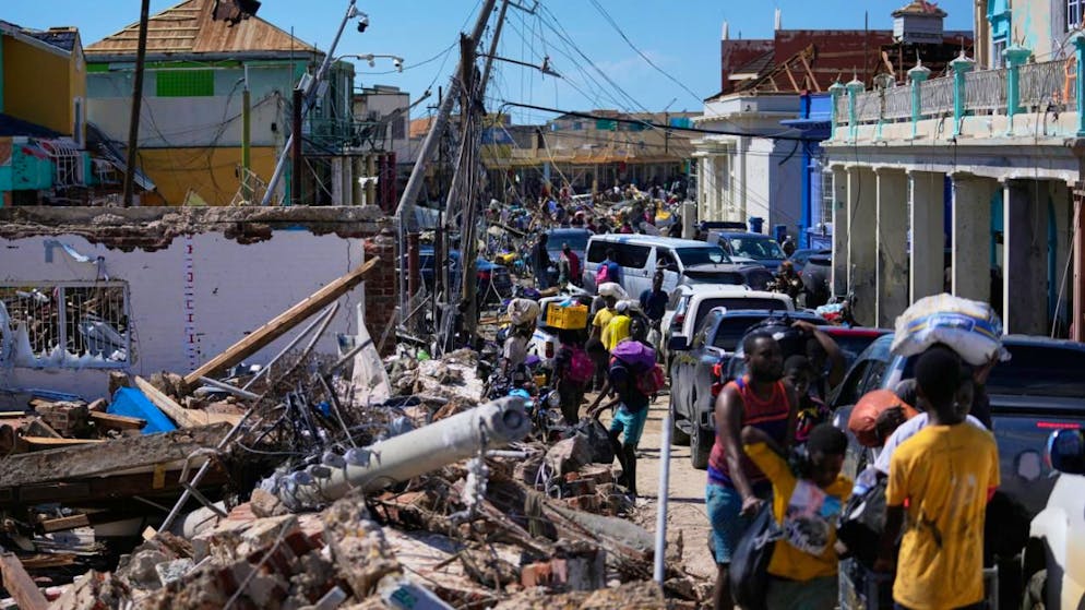 dpatopbilder - Bewohner verstopfen eine Straße in Black River nach dem Durchzug von Hurrikan Melissa. Foto: Matias Delacroix/AP/dpa
