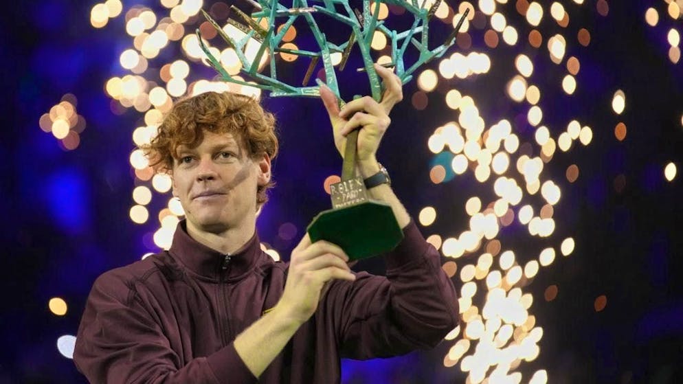 Jannik Sinner holds up the winner's trophy.