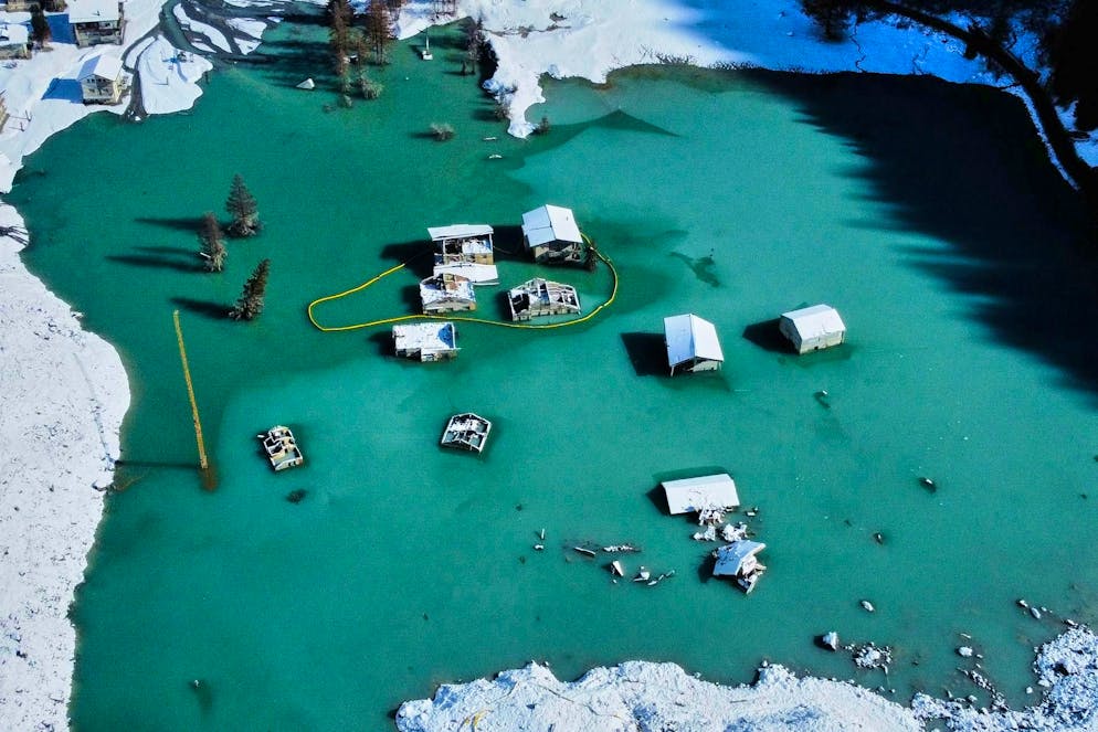 Solo i tetti sporgono dall'acqua verde turchese del lago appena formato.