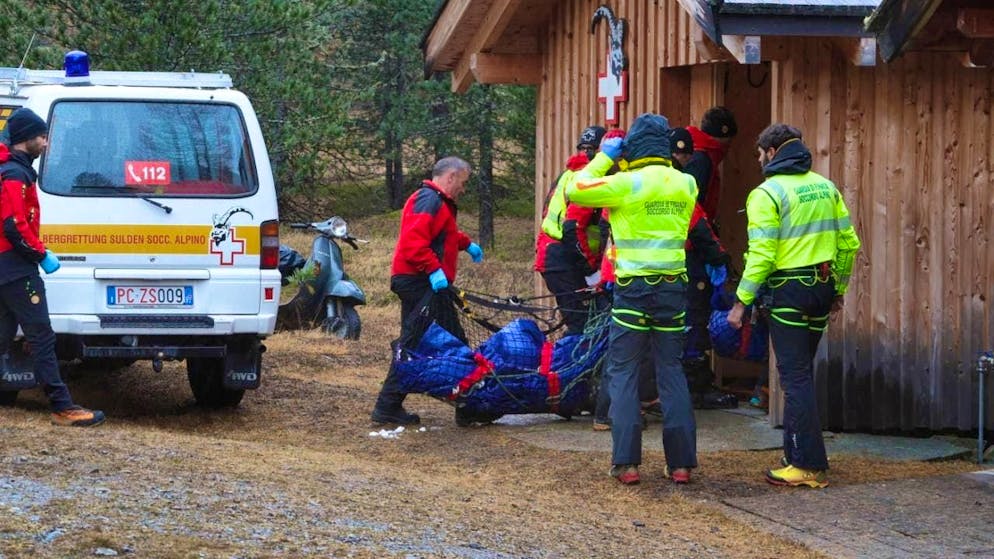 Two avalanche victims rescued from the mountain are carried to a hut after being brought down to the valley by a rescue helicopter. Photo: Karl-Josef Hildenbrand/dpa - ATTENTION: Use only in full format