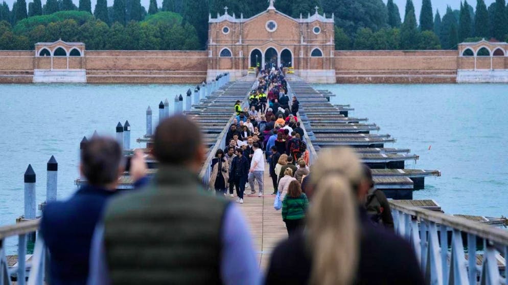 People cross the bridge that connects Venice to the cemetery on the island of San Michele. Photo: Luca Bruno/AP/dpa