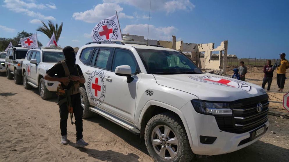 ARCHIV - Ein maskierter Hamas-Bewaffneter steht neben Fahrzeugen des Roten Kreuzes. Foto: Abdel Kareem Hana/AP/dpa/Symbolbild