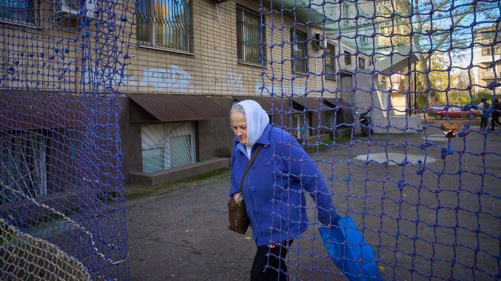 Eine Anwohnerin geht durch einem mit einem Anti-FPV-Drohnennetz bedeckten Hof in der Frontstadt Cherson in der Südukraine.