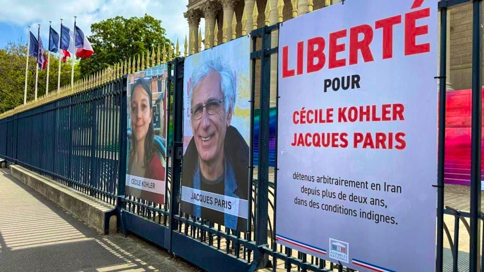 ARCHIVE - A poster and photos are displayed on a fence outside the French National Assembly calling for the release of Cécile Kohler and Jacques Paris. The couple were detained in Iran for more than three years. Photo: Rachel Boßmeyer/dpa - ATTENTION: For editorial use only in connection with current reporting and only with full attribution of the above credit