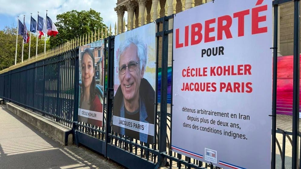 ARCHIV - Vor der französischen Nationalversammlung sind ein Plakat und Fotos an einem Zaun angebracht, mit denen die Freilassung von Cécile Kohler und Jacques Paris gefordert wird. Das Paar wurde mehr als drei Jahre im Iran in Haft festgehalten. Foto: Rachel Boßmeyer/dpa - ACHTUNG: Nur zur redaktionellen Verwendung im Zusammenhang mit der aktuellen Berichterstattung und nur mit vollständiger Nennung des vorstehenden Credits