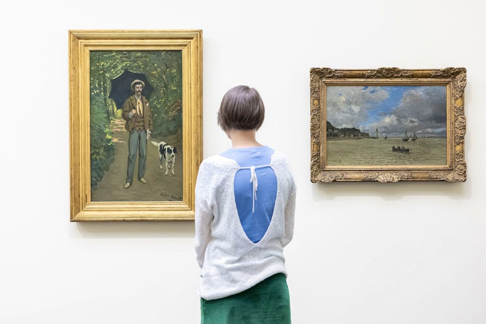 Une femme contemple l'œuvre « L'Homme à l'ombrelle » de Claude Monet, à gauche, à côté de l'œuvre « Le phare de Honfleur » de Claude Monet, à droite, au Kunsthaus Zurich, le jeudi 20 juin 2024 à Zurich, en Suisse. Le Kunsthaus Zürich vend le tableau « L'Homme à l'ombrelle » de Claude Monet : il s'est mis d'accord avec les héritiers d'un collectionneur juif. Ce dernier avait dû vendre l'œuvre pour se financer sa fuite devant le régime nazi, comme l'a annoncé mercredi le Kunsthaus. (KEYSTONE/Michael Buholzer)