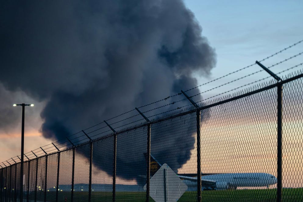 A UPS Boeing 737 is seen parked while a plume of smoke from the nearby UPS cargo plane crash is seen at Louisville Muhammad Ali International Airport on Tuesday, Nov. 4, 2025, in Louisville, Ky. (AP Photo/Jon Cherry)