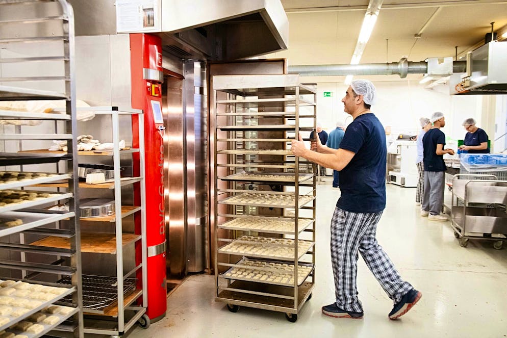 Panificazione UBS Helpetica. Davide spinge un carrello di biscotti nel forno.