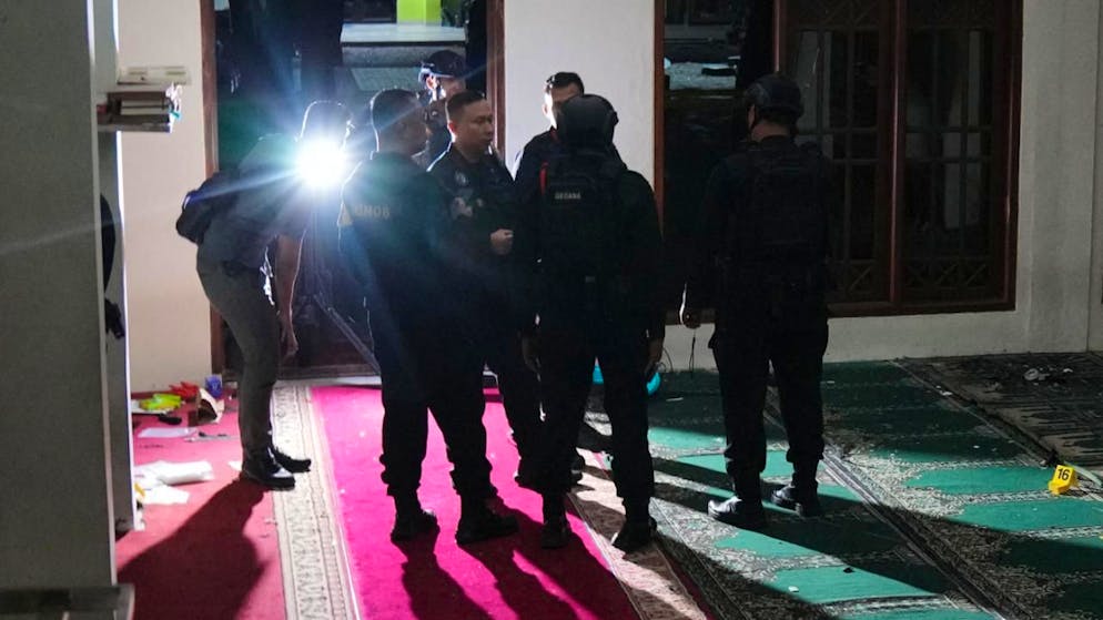 Des membres de l'équipe de déminage de la police indonésienne inspectent la mosquée où des explosions ont eu lieu dans l'enceinte d'un lycée à Jakarta.