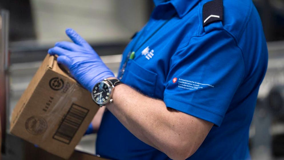 Un collaboratore dell'Ufficio federale della dogana e della sicurezza dei confini (UDSC) mentre controlla un pacchetto al centro postale di Zurigo-Mülligen
