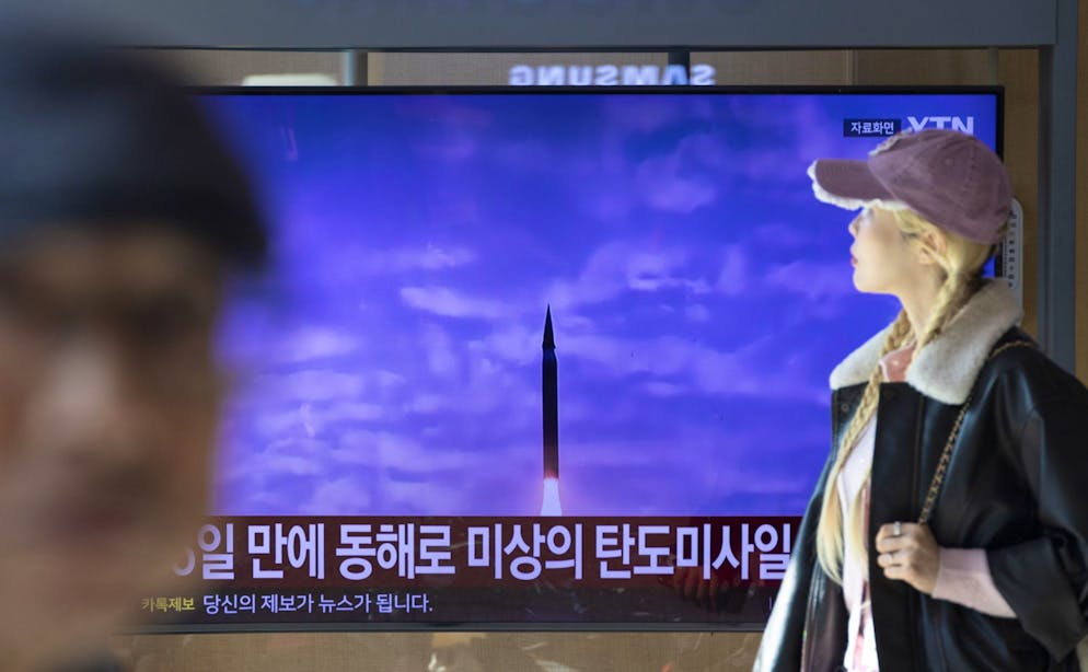 Des passants suivent les informations sur un écran de télévision dans une gare de Séoul, en Corée du Sud, le 7 novembre 2025.