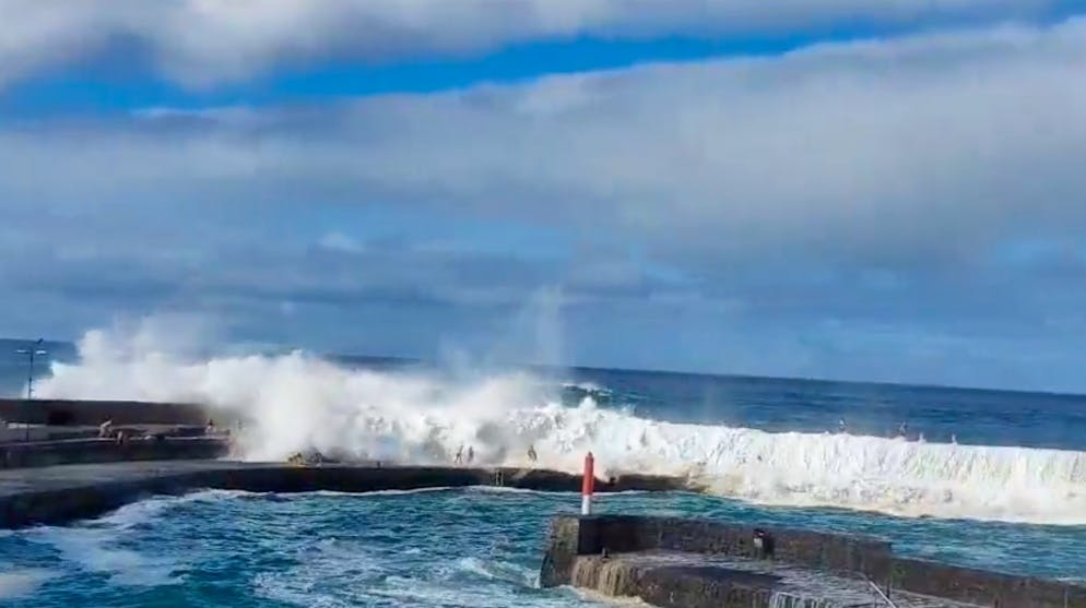 Eine Welle erfasst in Puerto de la Cruz auf Teneriffa Touristen und zieht sie ins Meer.