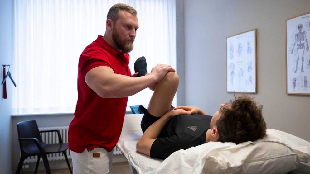 Die Branche "Gesundheits- und Sozialwesen" beschäftigte im 2024 die meisten Erwerbstätigen: Ein Therapeut bewegt das Knie eines Patienten im Behandlungsraum (Symbolbild).