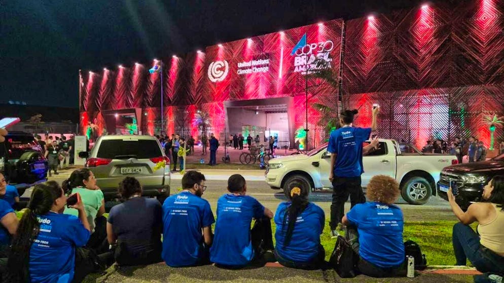Cleaners sit outside the venue of the UN Climate Summit COP30 after activists broke in and forced them to leave the site. Photo: Larissa Schwedes/dpa