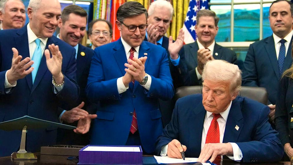 US President Donald Trump signs the interim budget in the Oval Office on Wednesday evening - behind him, Majority Leader Mike Johnson and other Republican members of the US House of Representatives applaud.