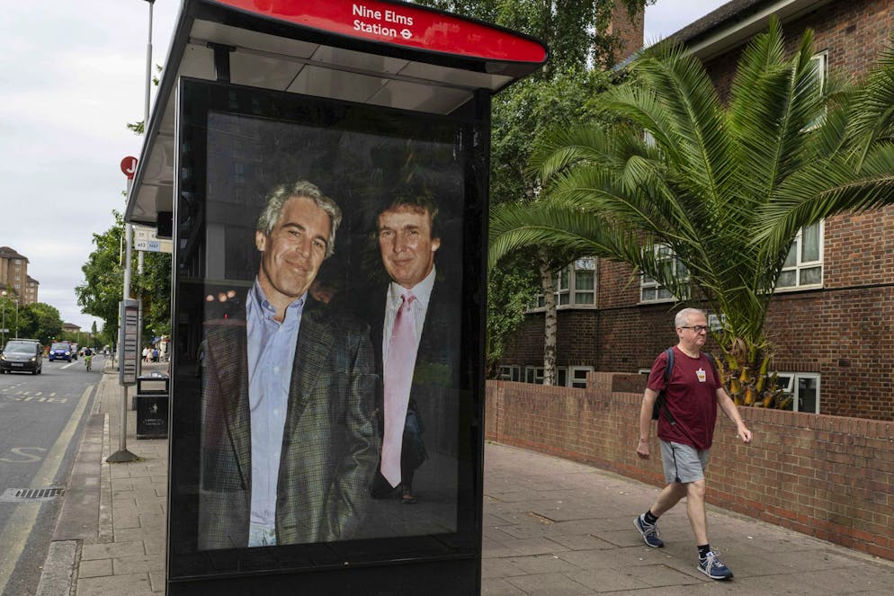 Degli attivisti affiggono un manifesto che ritrae il presidente Donald Trump e Jeffrey Epstein.