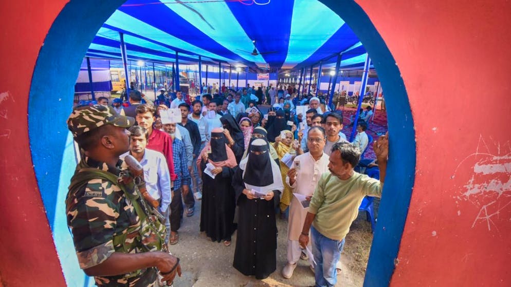 ARCHIV - Menschen stehen in einer Schlange, um ihre Stimme für die Wahlen in Bihar abzugeben. Foto: Uncredited/AP/dpa