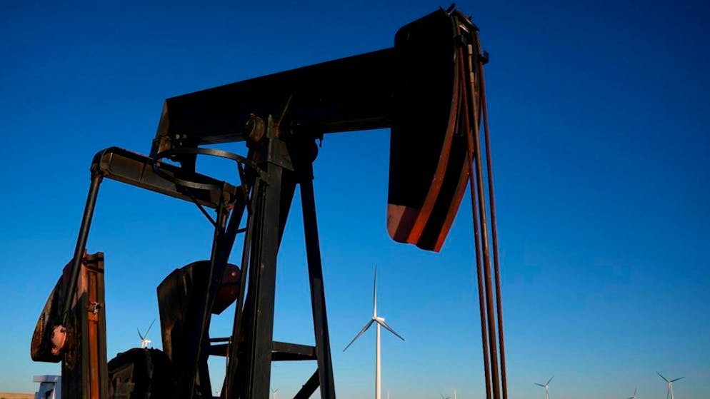 ARCHIV - Eine Tiefpumpe arbeitet im Vordergrund, während sich in der Ferne die Windturbinen des Buckeye Wind Energy Windparks erheben. Auf der Klimakonferenz in Brasilien sind auch viele Öl-Lobbyisten akkreditiert. Foto: Charlie Riedel/AP/dpa