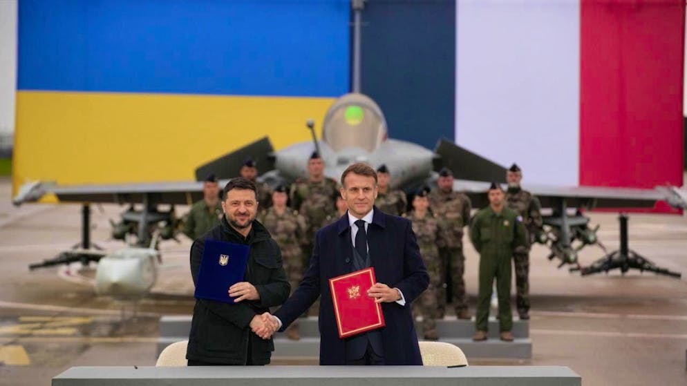 French President Emmanuel Macron (r) and Ukrainian President Volodymyr Zelensky shake hands after signing an agreement at Villacoublay airbase near Paris. Photo: Christophe Ena/Pool AP/dpa