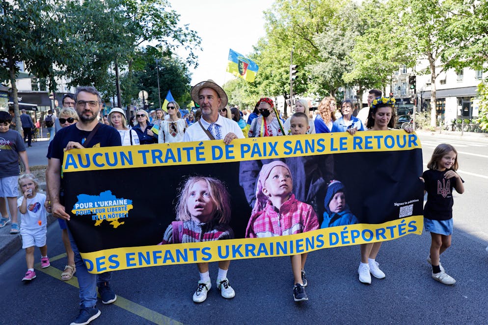 Des personnes brandissent une banderole sur laquelle on peut lire « Pas de traité de paix sans le retour des enfants ukrainiens déportés » lors d'un rassemblement en soutien à l'Ukraine, à l'occasion de la fête nationale ukrainienne, à Paris, le 24 août 2025. Plusieurs familles d'enfants ukrainiens déportés de force en Russie le 17 novembre 2025 ont tiré la sonnette d'alarme sur leur sort, affirmant que tout contact avait été coupé, et ont appelé à un soutien international. Lors d'une conférence de presse exceptionnelle à Paris, Darina Repina, la tutrice légale de deux enfants emmenés de force en Russie après l'invasion à grande échelle de l'Ukraine par Moscou en 2022, a déclaré que les autorités russes ignoraient toutes les demandes visant à faciliter le retour des enfants.