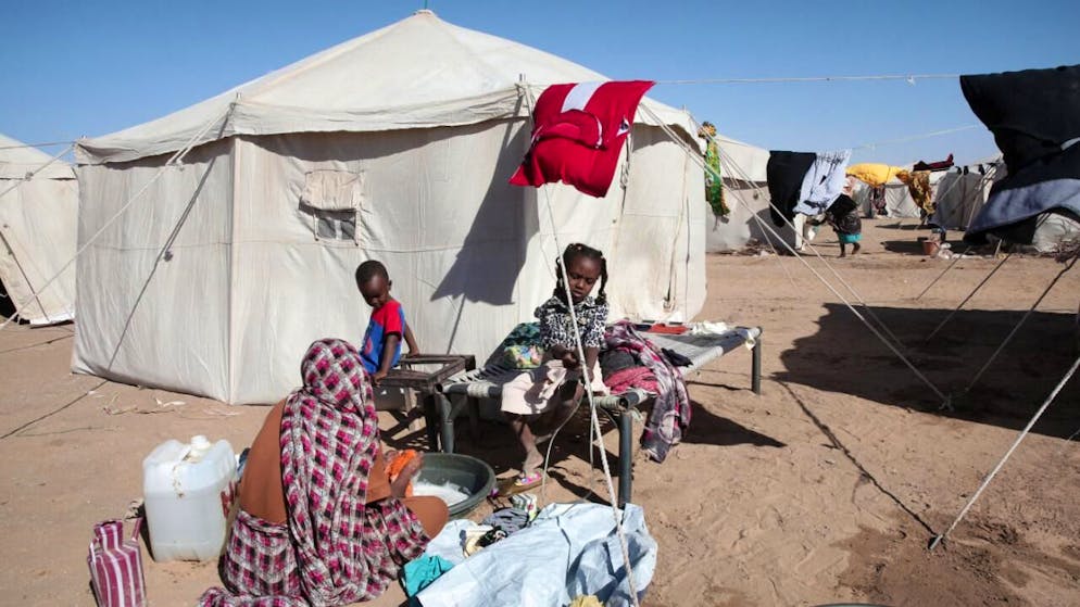 Una donna e dei bambini sudanesi vicino a una tenda
