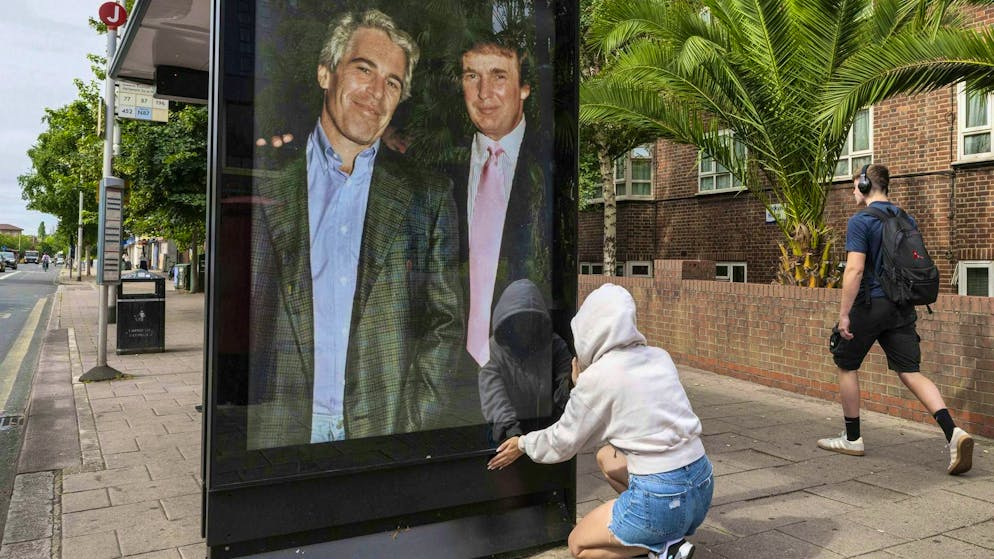 Activists install a poster showing US President Donald Trump with sex offender Jeffrey Epstein at a bus stop near the US embassy in London. (July 17, 2025)