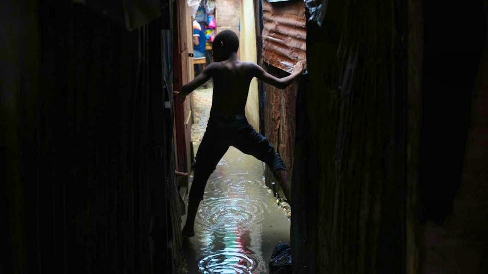 A boy moves in an alley flooded by rain from Hurricane Melissa in an emergency shelter for families displaced by gang violence. Photo: Odelyn Joseph/AP/dpa
