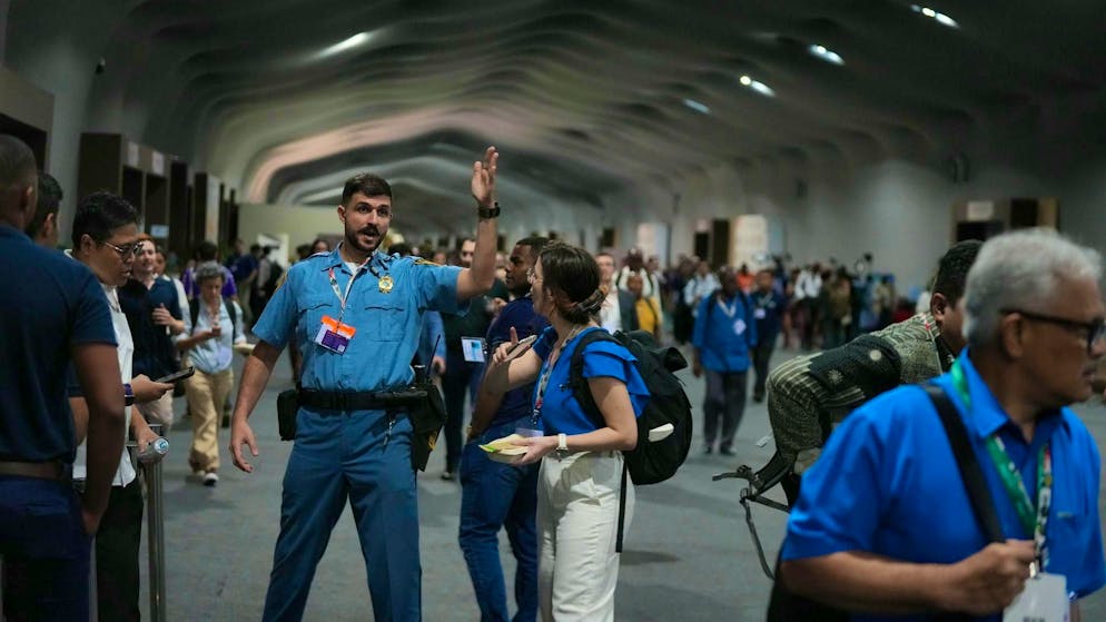 People leave the grounds of the COP30 world climate conference because of a fire.