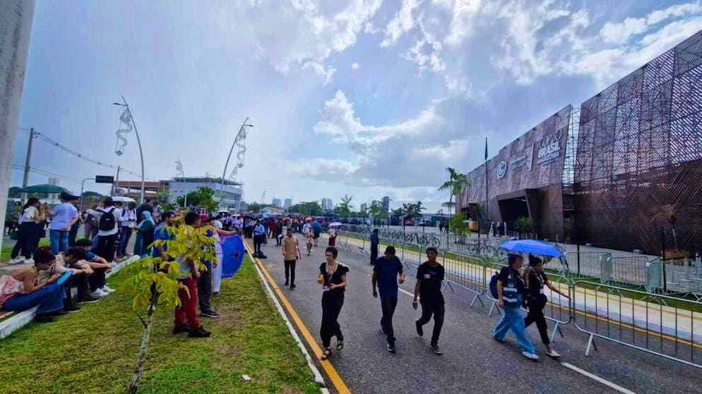People sit in front of a pavilion at the COP30 World Climate Conference. Photo: Larissa Schwedes/dpa
