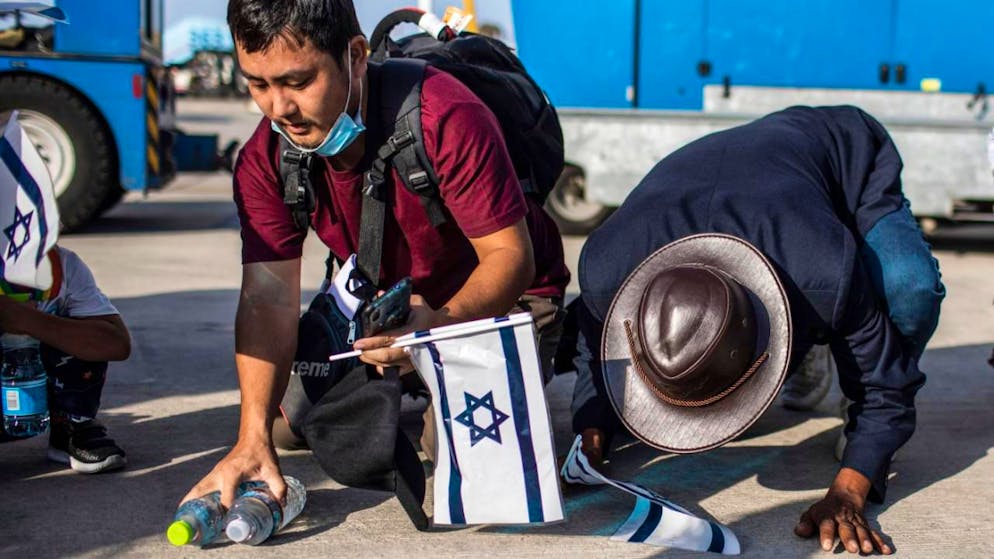 ARCHIV - Indische Immigranten der «Bnei Menashe» halten israelische Flaggen und knien bei ihrer Ankunft am Flughafen Ben Gurion auf dem Boden. Foto: Ilia Yefimovich/dpa