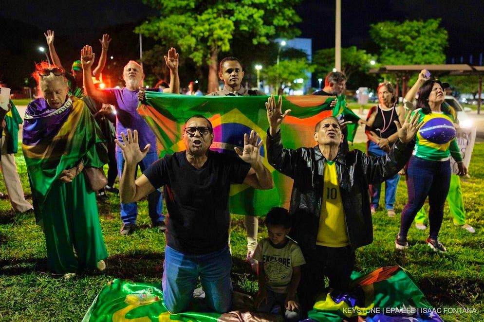 Supporters of former Brazilian President Jair Bolsonaro pray in front of the federal police headquarters in Brasília on November 22, 2025, where the ex-president is being held after his arrest.