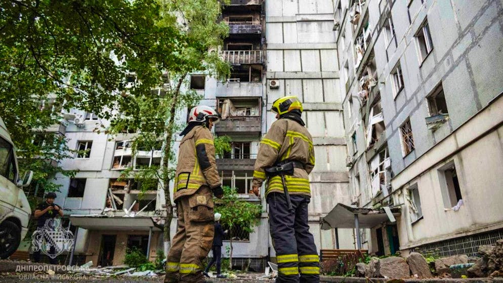 HANDOUT - In this photo provided by the Dnipropetrovsk military regional administration via AP on Saturday, Sept. 20, 2025, rescue workers stand in front of a residential building damaged after a Russian attack on Dnipro, Ukraine. Photo: Dnipropetrovsk military regional/Dnipropetrovsk military regional administration/dpa - ATTENTION: For editorial use only and only with full attribution of the above credit
