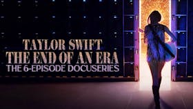 Taylor Swift, in einem glitzernden Fransen-Outfit und Stiefeln, geht durch eine hell erleuchtete Tür am Ende einer Bühne, zur Bewerbung ihrer 6-teiligen Doku-Serie The End of an Era.