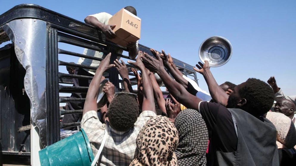 Familien, die aus El-Fasher vertrieben wurden, greifen nach Lebensmitteln, die Helfer im Lager El-Afadh in Al Dabbah im nördlichen Sudan Nahrungsmittel verteilen. (Archivbild)