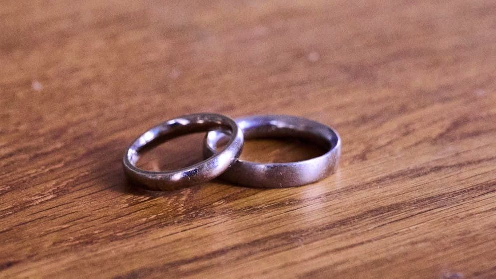 ARCHIVE - Wedding rings lie on a wooden table (archive photo). Photo: Annette Riedl/dpa