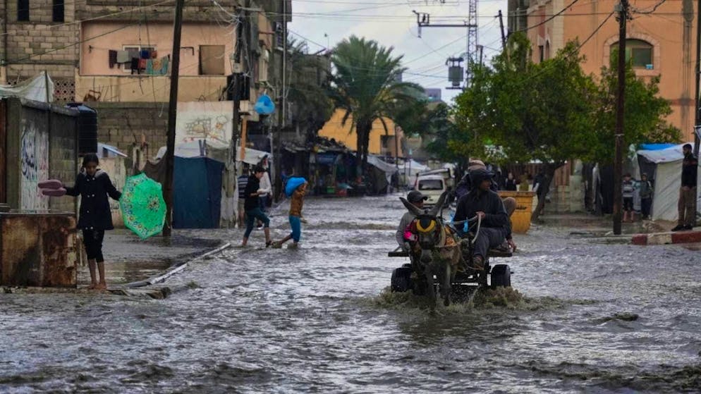 Palestinians walk through a flooded street after heavy rains in Deir al-Balah, central Gaza Strip. Photo: Abdel Kareem Hana/AP/dpa