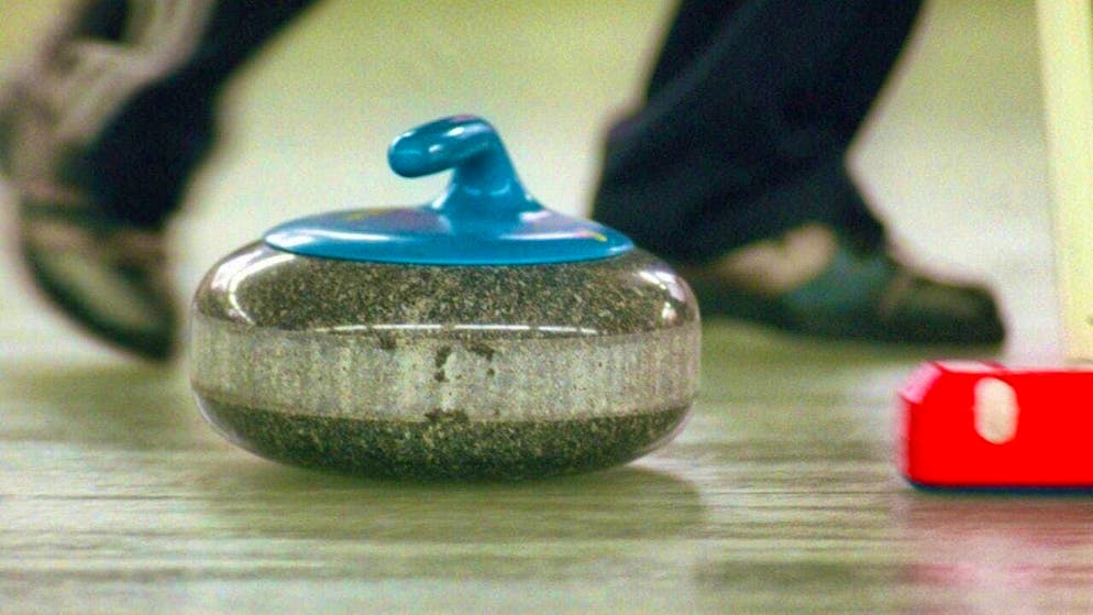 The curling stone glides across the ice