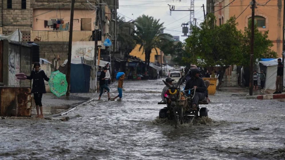Palästinenser gehen durch eine überschwemmte Straße nach starken Regenfällen in Deir al-Balah, im zentralen Gazastreifen. Foto: Abdel Kareem Hana/AP/dpa
