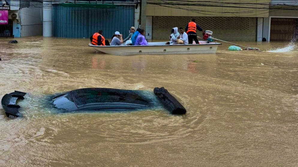 Thai rescue workers move on a boat past a car submerged in floodwaters in the southern Thai province of Songkhla. Photo: Uncredited/AP/dpa
