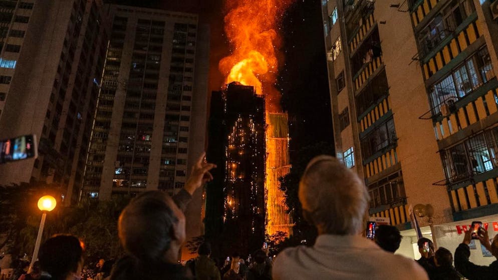 dpatopbilder - Menschen betrachten die Flammen, die ein Gebäude verschlingen, nachdem im Wang Fuk Court, einer Wohnsiedlung im Stadtteil Tai Po in den New Territories von Hongkong, ein Feuer ausgebrochen ist. Foto: Chan Long Hei/AP/dpa
