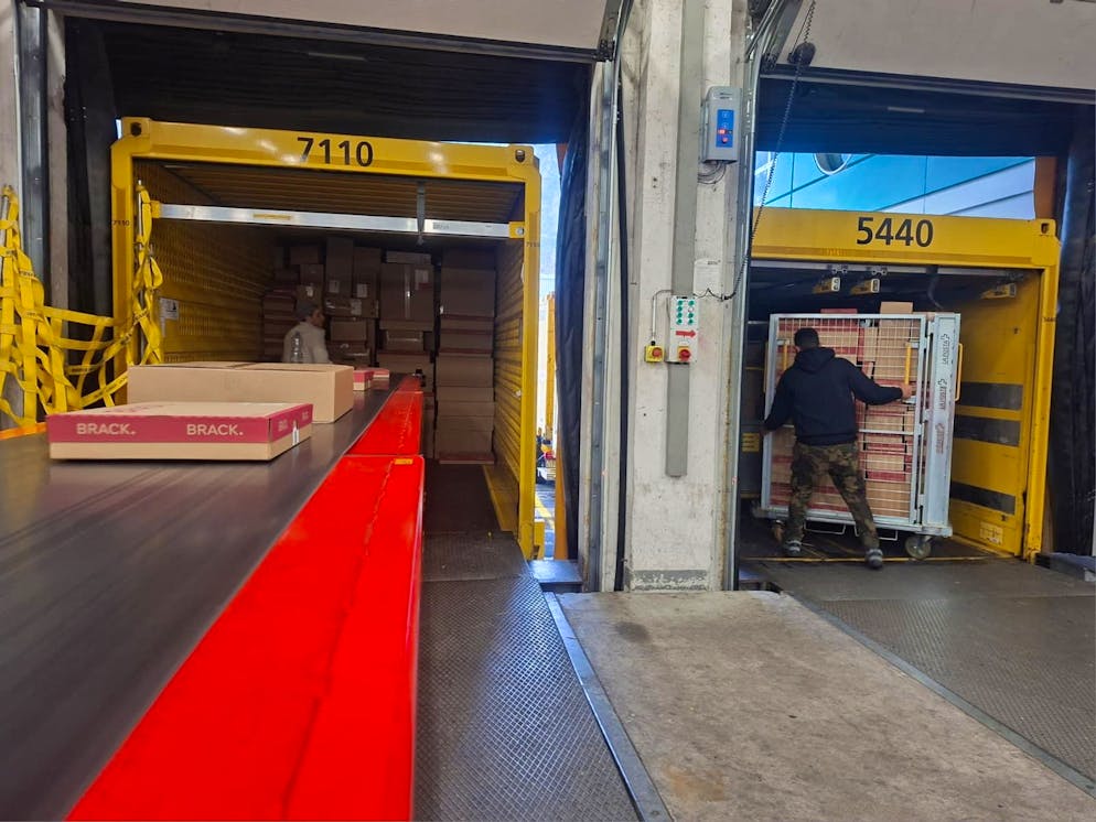 Per Fliessband werden die fertigen Pakete zum Lkw gebracht und von einem Mitarbeiter verladen.