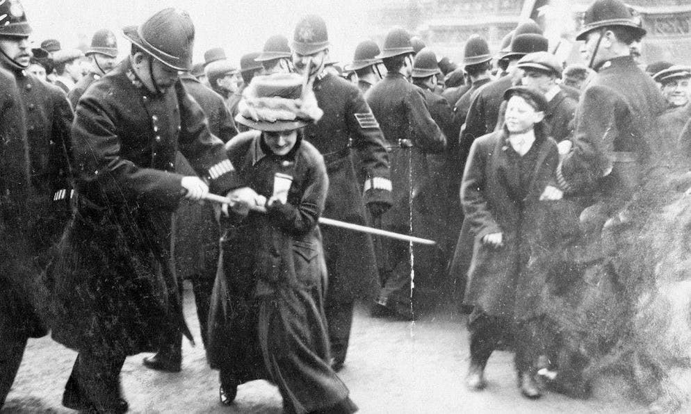 A policeman snatches a suffragette's banner.